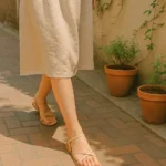 햇살 속 베이지 스트랩 샌들에 집중된 감성적인 발걸음