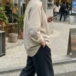 봄 하객룩 - 베이지와 오트밀 컬러가 섞인 부드러운 셔츠에 와이드 슬랙스를 매치하고 무심하게 걷는 도시적인 룩북 컷