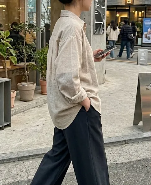 봄 하객룩 - 베이지와 오트밀 컬러가 섞인 부드러운 셔츠에 와이드 슬랙스를 매치하고 무심하게 걷는 도시적인 룩북 컷