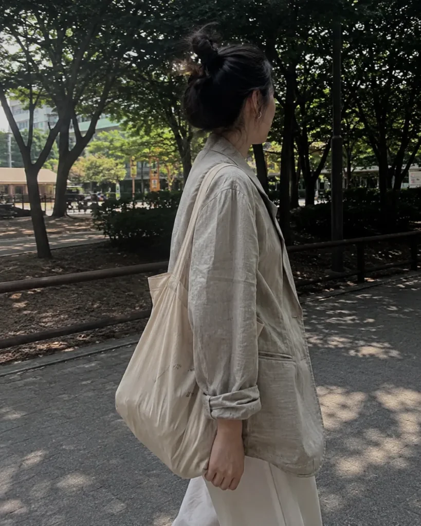 여름가디건 - 공원 산책로에서 린넨자켓과 캔버스 토트백을 착용한 여성의 옆모습