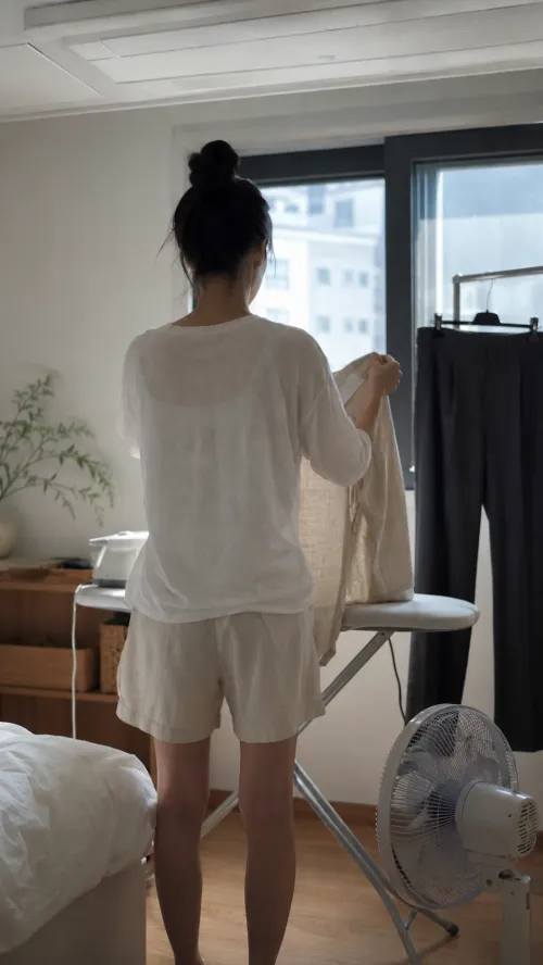 원룸에서 다림질하다 만 린넨 셔츠와 선풍기가 켜진 출근 준비 풍경